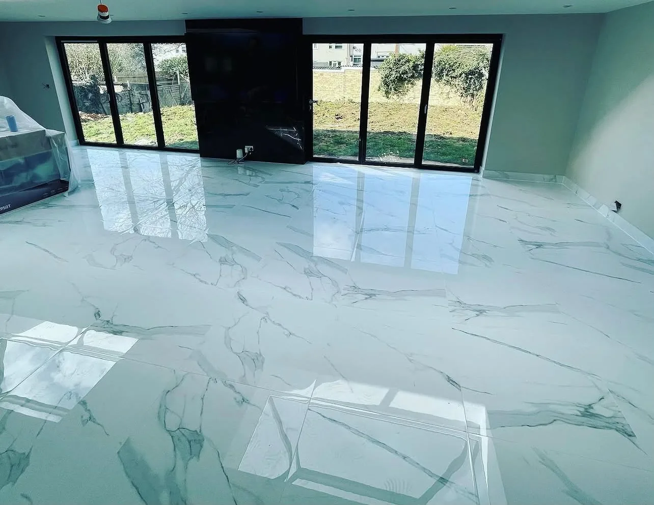 Open-plan living space with polished marble-effect porcelain floor and black bifold doors